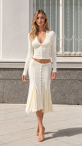 Front view of model wearing cream long-sleeve knit cardigan and pleated mermaid midi skirt set