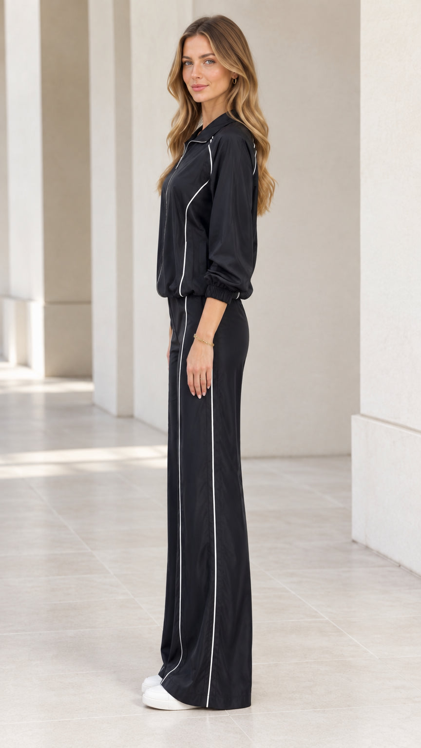 Side view of woman wearing black zip-up tracksuit set with contrast piping