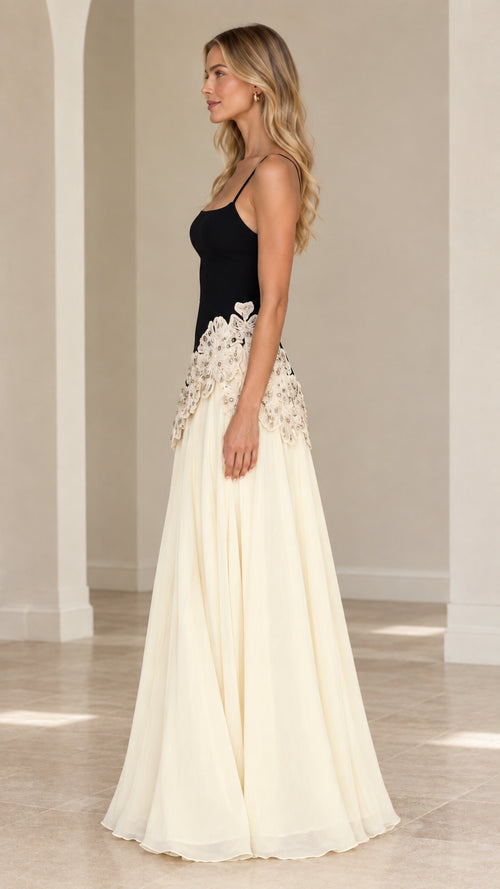 Side 3/4 view of black and cream maxi dress showing waistline embroidery and flowing skirt