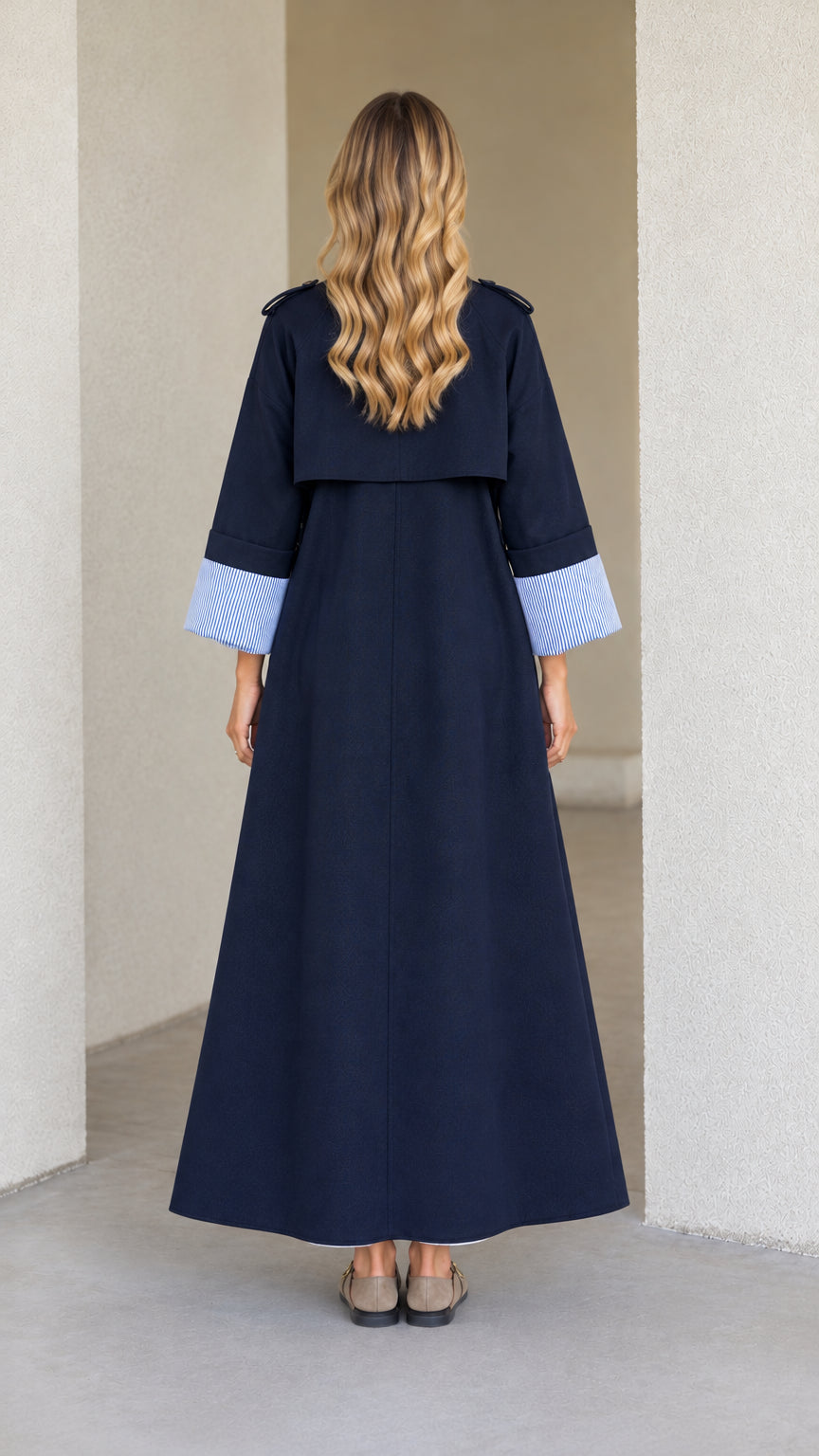 Back view of model wearing Navy Blue maxi trench coat featuring storm flap detail