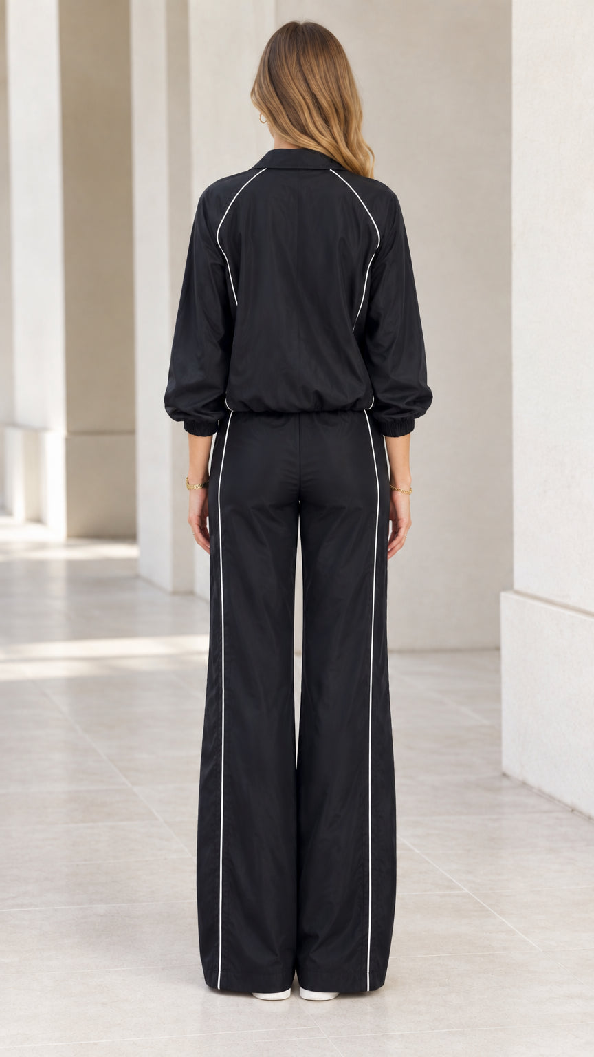Back view of woman wearing black two-piece tracksuit set with wide-leg trousers