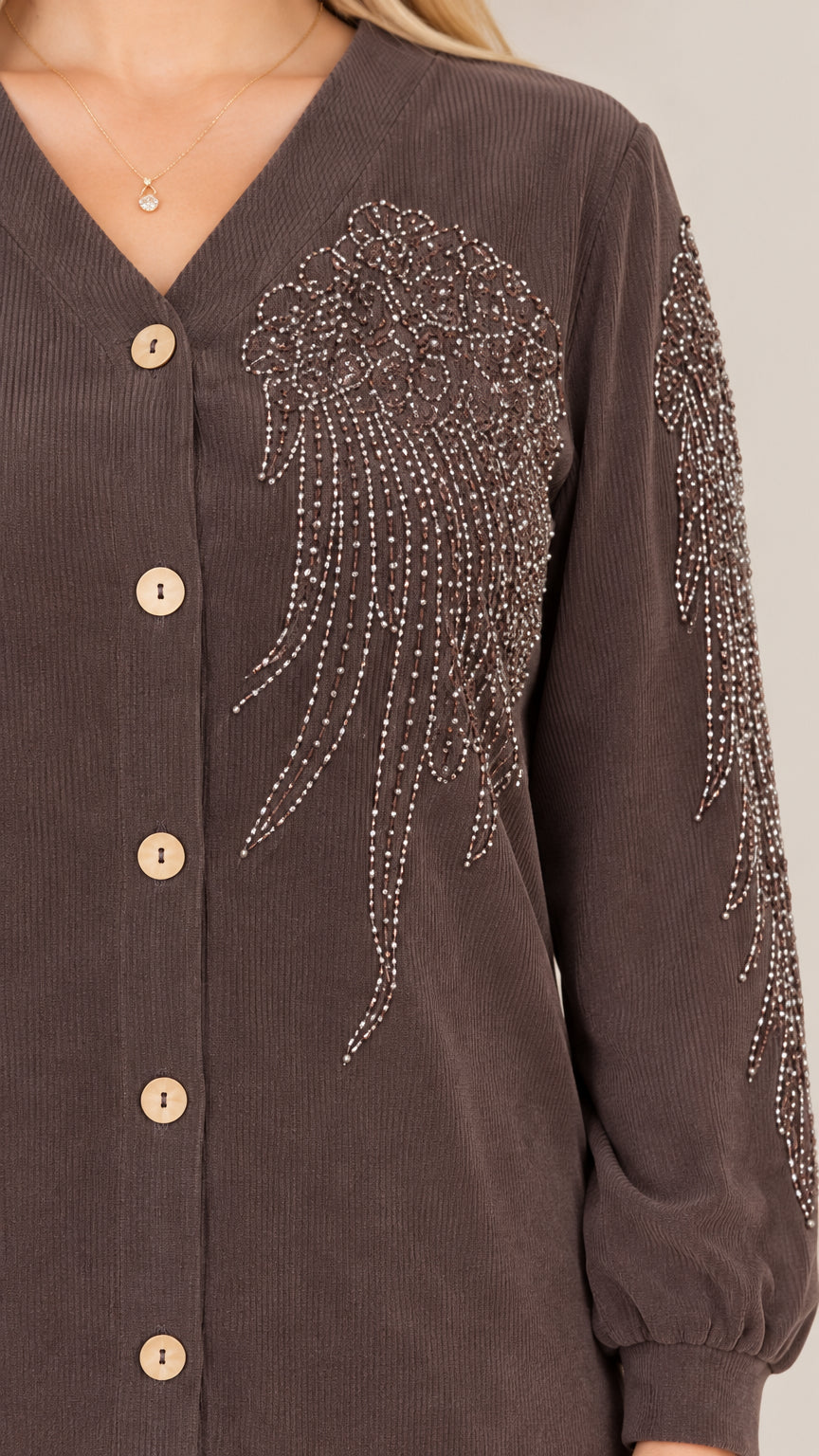 Close-up detail of rhinestone and beaded embellishment on brown ribbed fabric and button placket