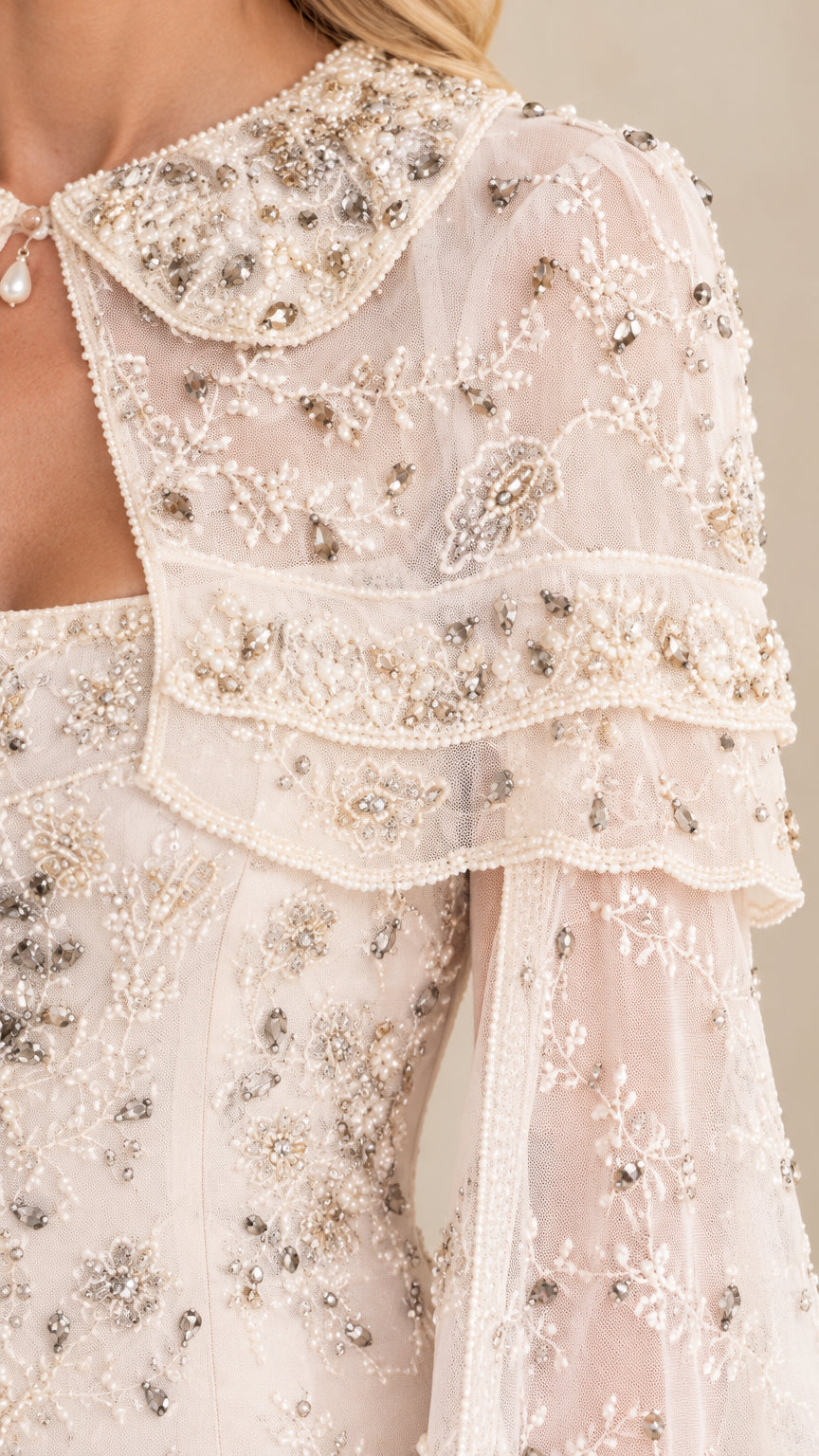 Close-up detail of collar, capelet, and beading craftsmanship on cream dress