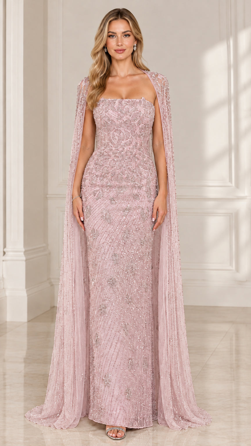 Front view of woman wearing blush pink strapless embellished evening dress with cape overlay